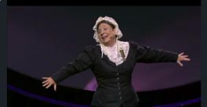 Candy Campbell in her character portrayal of Florence Nightingale wears a black skirt and jacket, white lace cap and collar
