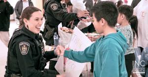 Police woman smiling as young boy gave her flowers and a thank you card