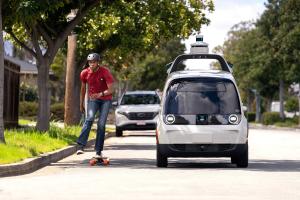 Image of a Nuro bot on the road with a skateboarder sharing the road.
