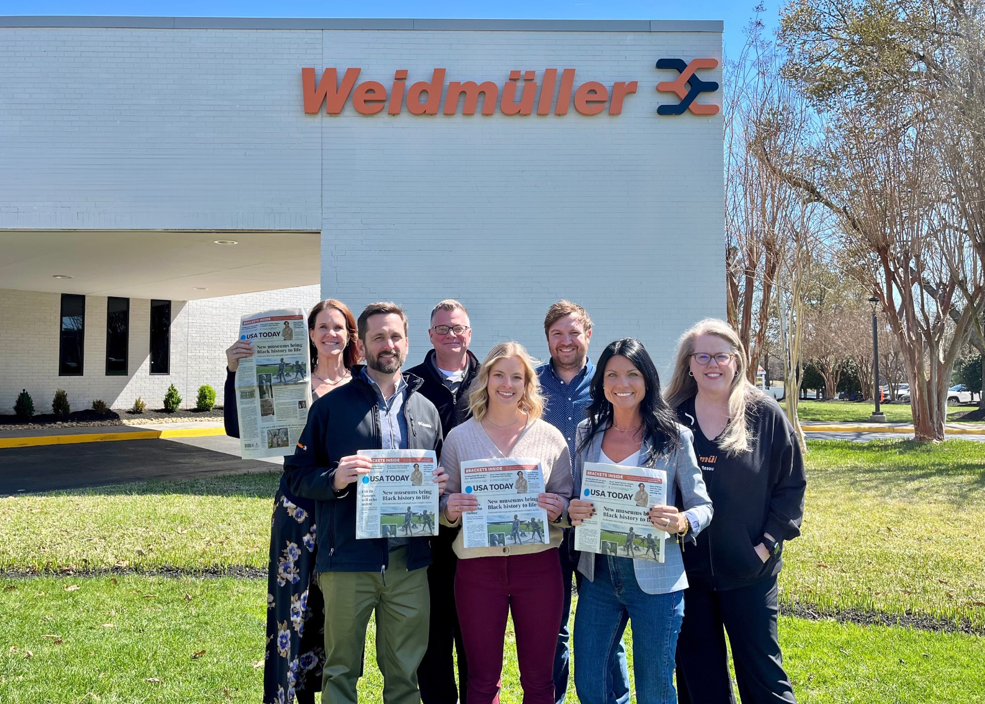 People holding a newspaper outside a building