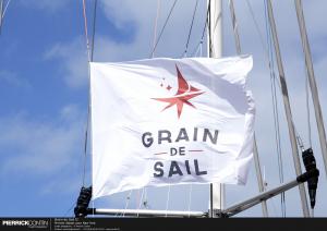 White flag with the words "Grain de Sail" waving in the wind