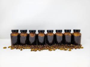 a row of gelcap bottles filled with 100 gelcaps each, with lids on, no labels, and loose gelcaps laying in front of them