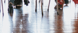A group of friends seated for a dinner party in a loft, with only their legs visible, showcasing the newly repaired hardwood floor.