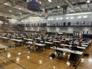 A high school gym filled with students sitting at tables waiting to start the competition.