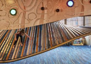 Child walking on colorful wooden boards of the Climb playscape at the Children's Museum of Tacoma