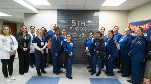 Image of 16 nurses and students standing in front of 5th floor surgical specialty unit sign.