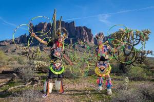 Two Native American men pose in full regalia with their hoops in the desert