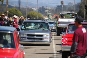 Lots of cars and trucks parading around the Del Mar Fairgrounds. 