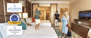 A little boy jumping in a bed in a hotel room with his parents.