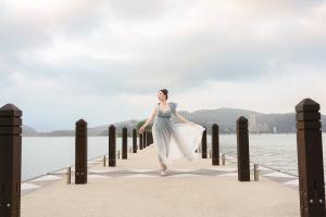 Christine walks on a Sun Moon Lake bridge, her grey dress waving in the breeze.