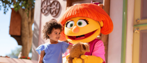 Julia interacting with a young girl while holding a toy animal at Sesame Place Parks.