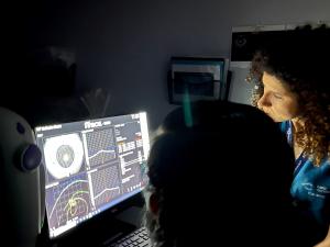 Eye care doctors in a dark room looking at an eye scan on a computer screen