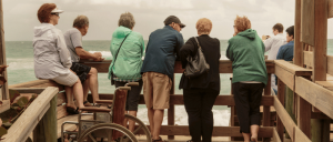 A group of elderly people looking over the sea.