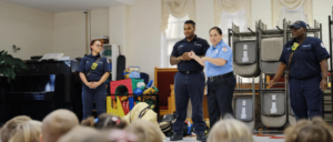 A group of firefighters talking in front of children.
