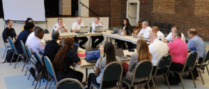 A number of people in a room having a meeting.