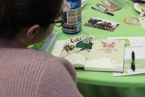 Person looking at notebook of artwork at the Symposium