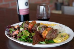 Perfectly cooked filet mignon kabobs on an oval plate served with grilled veggies, fresh green salad, and long grain basmati rice