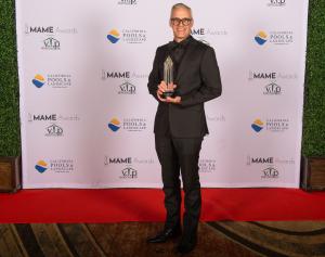 Leland Grise holds MAME Award on stage