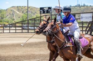 Two polo players engage in ride-off on horseback during polo game