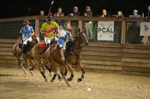three polo players ride after a ball on horseback during play