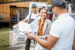 Two skilled movers facilitating furniture transport during relocation, with a female customer smiling amidst the process.