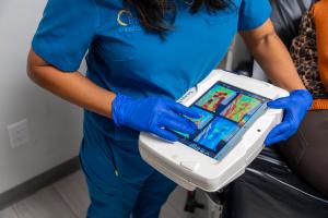 Close up of the imaging device, SnapshotNIR, in the hands of a doctor. Device image shows 4 frames of the hemoglobin picture.