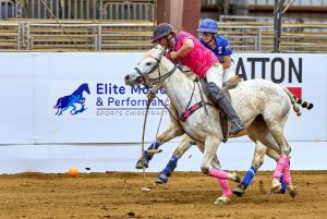 Two polo players ride after ball on horseback during an arena polo game