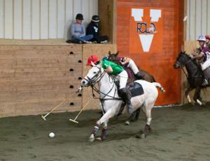 two arena polo players go for a ball at goal