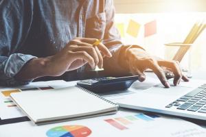 Person with a normal calculator using an online calculator to help with financial decision making process.