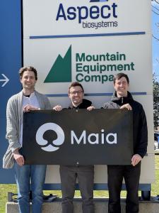 The Maia Farms team stands on a platform, holding a banner with the Maia Farms logo