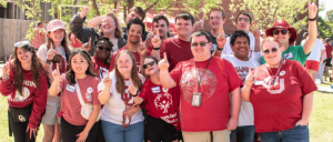 A photo of Zarrow Institute students smiling while raising their point fingers.