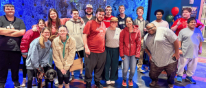 A photo of the Zarrow Institute students and staff together with a black dog.