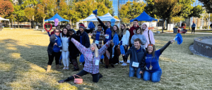 Zarrow Institute students holding blue cheerleading pompoms at the university grounds.