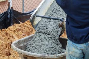 Ready-mix concrete being poured from a truck into a concrete pump at a construction site