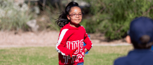 A young girl wearing a red jacket running towards an adult.