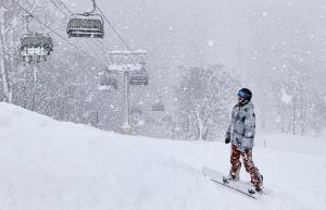 snowboarder looking at quad lift on powder filled day in Niseko