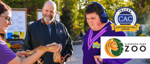 A staff member from Elmwood Park Zoo holding a snake while showing it to the guests.