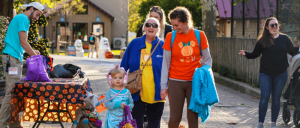 A young girl, wearing a blue princess costume, is exploring Elmwood Park Zoo with her smiling adult guardians.