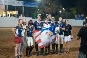 arena polo players celebrate with the USA flag after winning