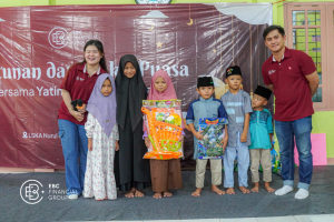 Two EBC employees posing with a group of orphans, displaying food aid packages.