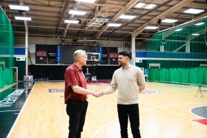 Kevin Routledge, Chairman of Leicester Riders and Mattioli Arena, and Jas Hayer, Global Sales Director of Cyferd, shaking hands on the Leicester Riders court