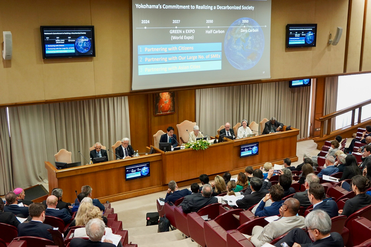 Mayor Takeharu Yamanaka of Yokohama City seated, giving a presentation in front of a seated audience of mayors, governors, and other local leaders at the Vatican climate summit