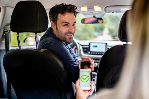 a driver getting paid via app showing green tick checking recipt from passenger on the back seat 