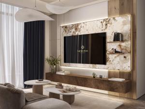 Modern and elegant living room designed by Fajr Interiors, featuring a large wall-mounted TV, stylish marble accents, contemporary furniture, and tasteful decor elements.