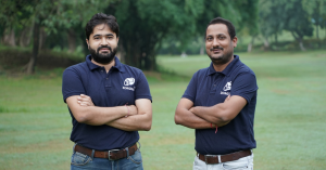 Two men standing in a field and smiling at the camera