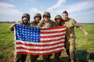 Actors from Band of Brothers television series holding a commemorative 48 star firebrand flag in the jump landing zone outside of Carentan, France.