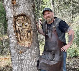 man standing next to wood carving