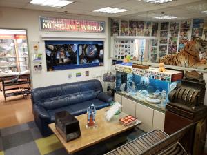General view of the museum with a blue sofa, an industrial bench and a nice wagon table next to a prehistoric aquarium fossils of ammonites. There are photos of Boopy space trip on the wall behind the sofa and photos of Boopy's past projects with children