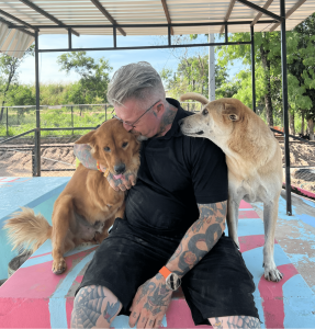 Michael J. Baines cuddles two of the dogs in his care inside the Sanctuary