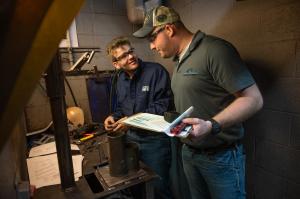 Cody W. Wolfe (right), an instructor of welding and a judge for the competition, checks in on one of the competitors.